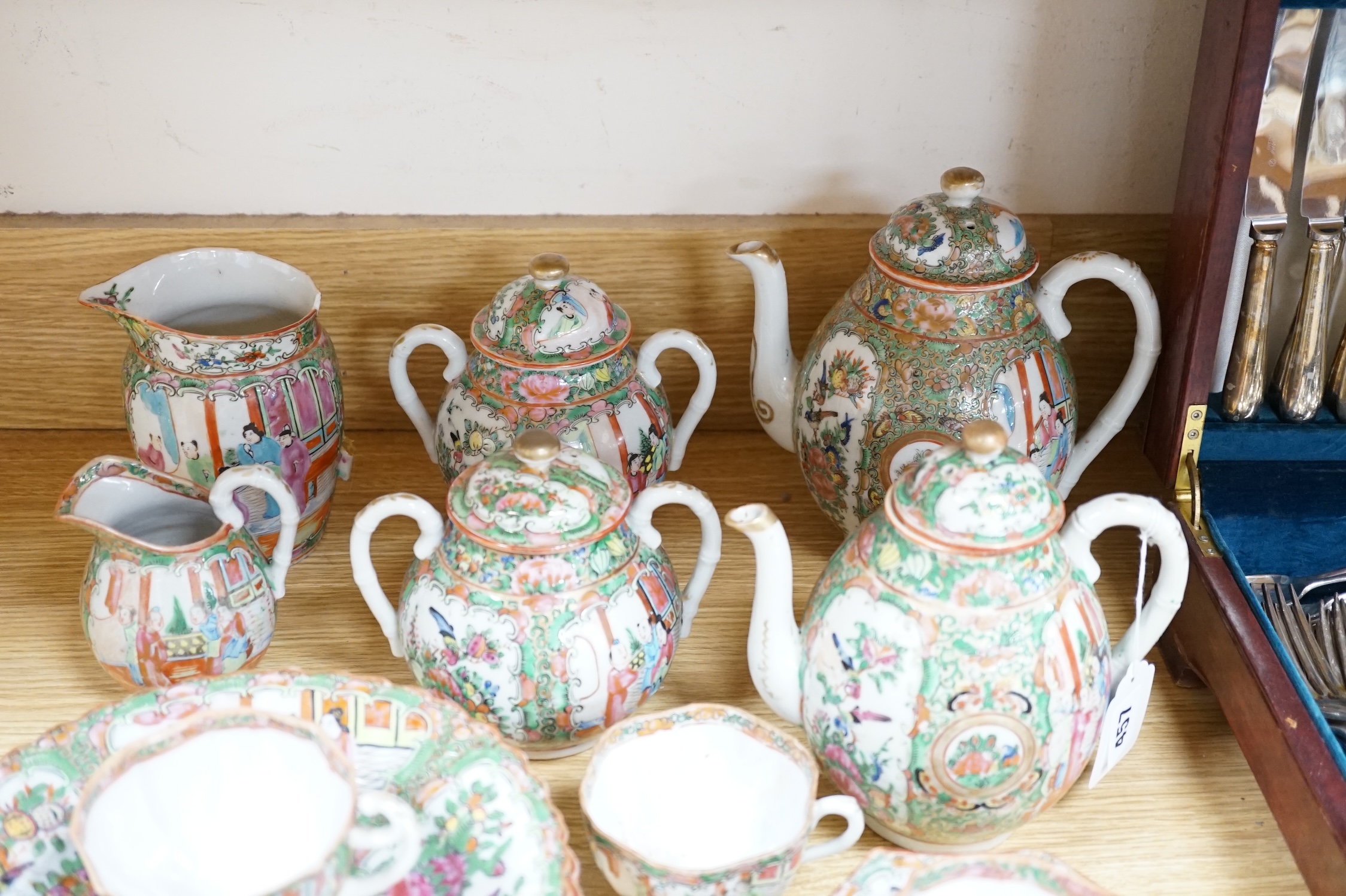 A Chinese famille rose six place setting tea service, including a large tea pot and cover, a smaller water pot and cover, two sugar bowls with covers, a large milk jug (handle broken) a small cream jug and a cake plate,(